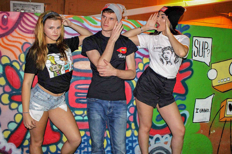 Three friends in Tough Culture tees by a mural